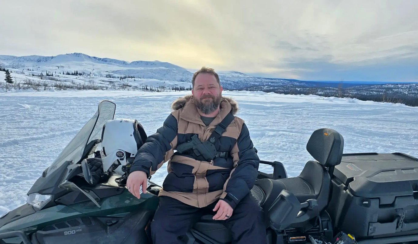 Chris on a snowmachine in the Alaska mountains